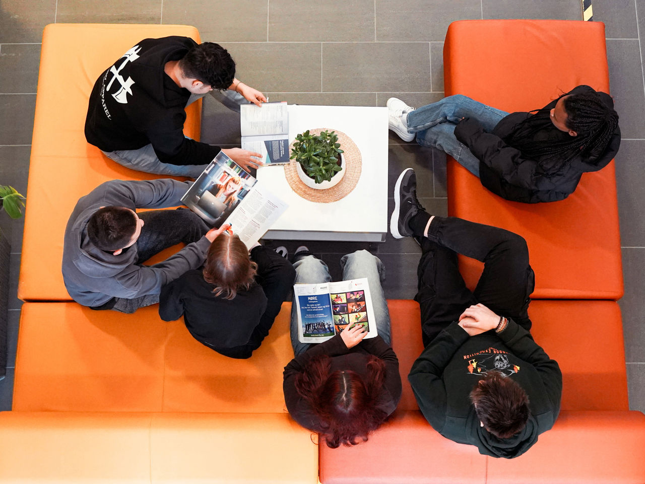 Gruppe elevar som sit i foajeen på skulen