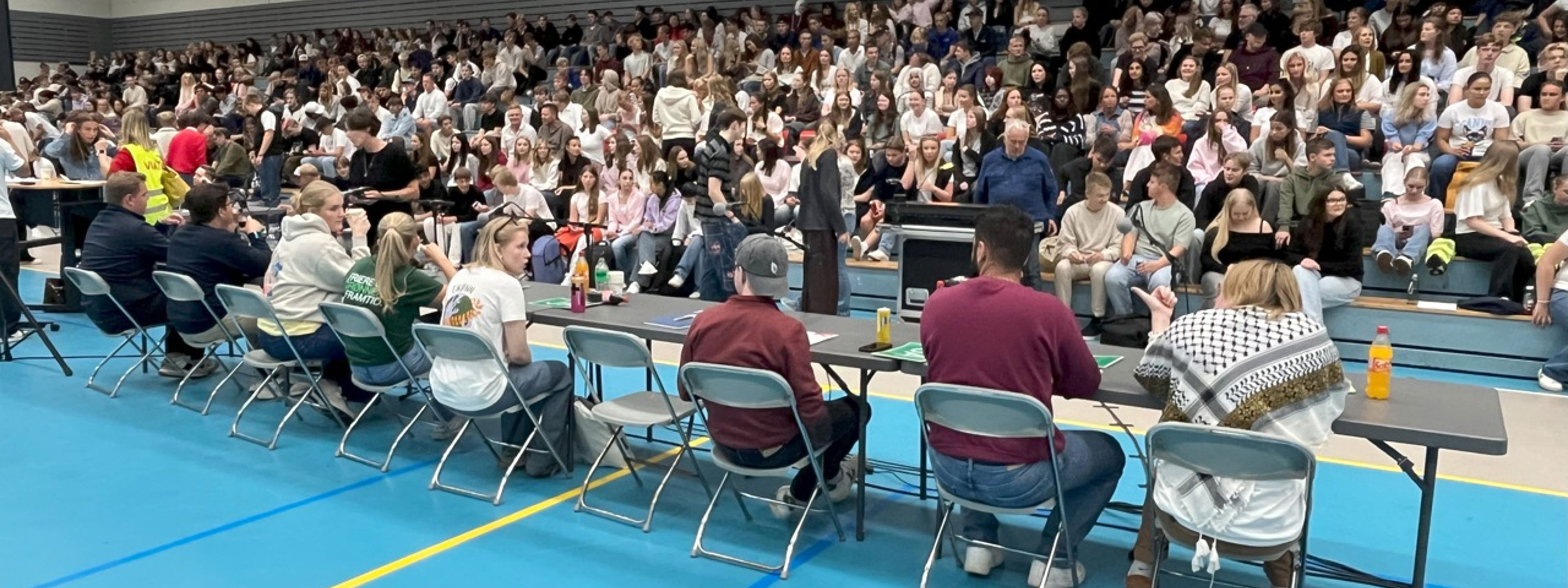 Representantar for ungdomsparti sitjande ved debattborda